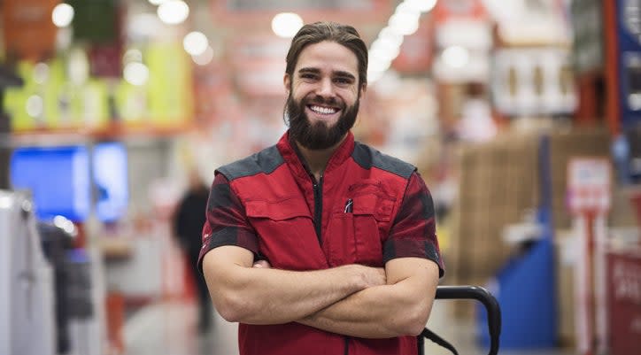 man in a hardware store smiling with his arms crossed