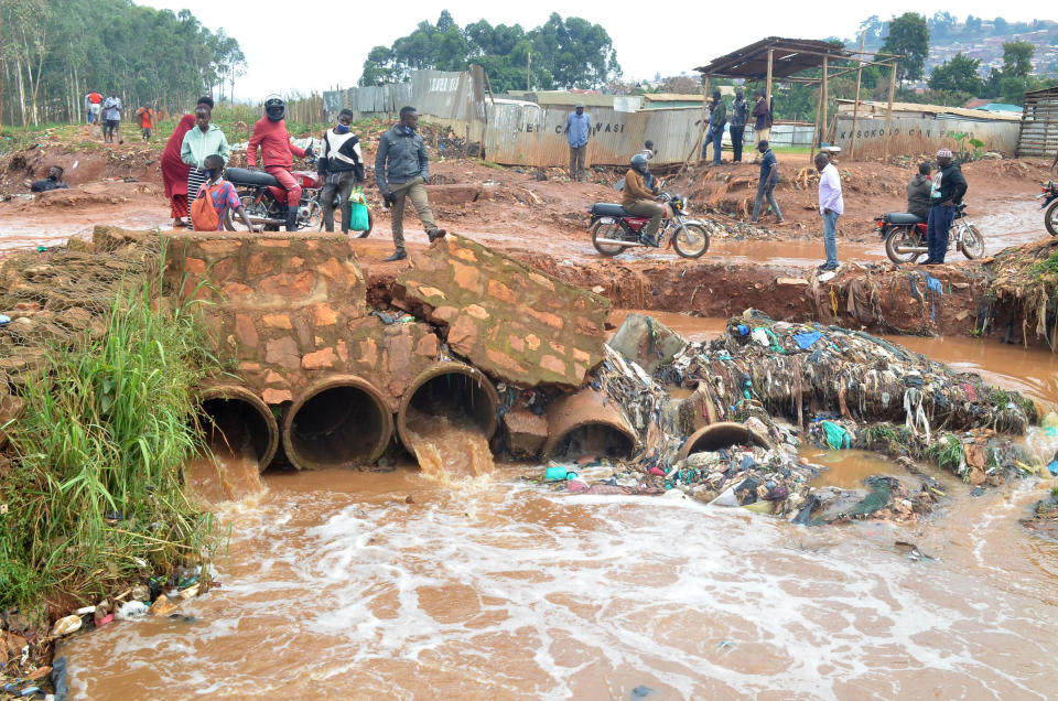 People stand on a damaged bridge in the wake of flood triggered by heavy rain in Kampala, Uganda, Aug. 9, 2021.<span class="copyright">Nicholas Kajoba—Xinhua News Agency/Redux</span>