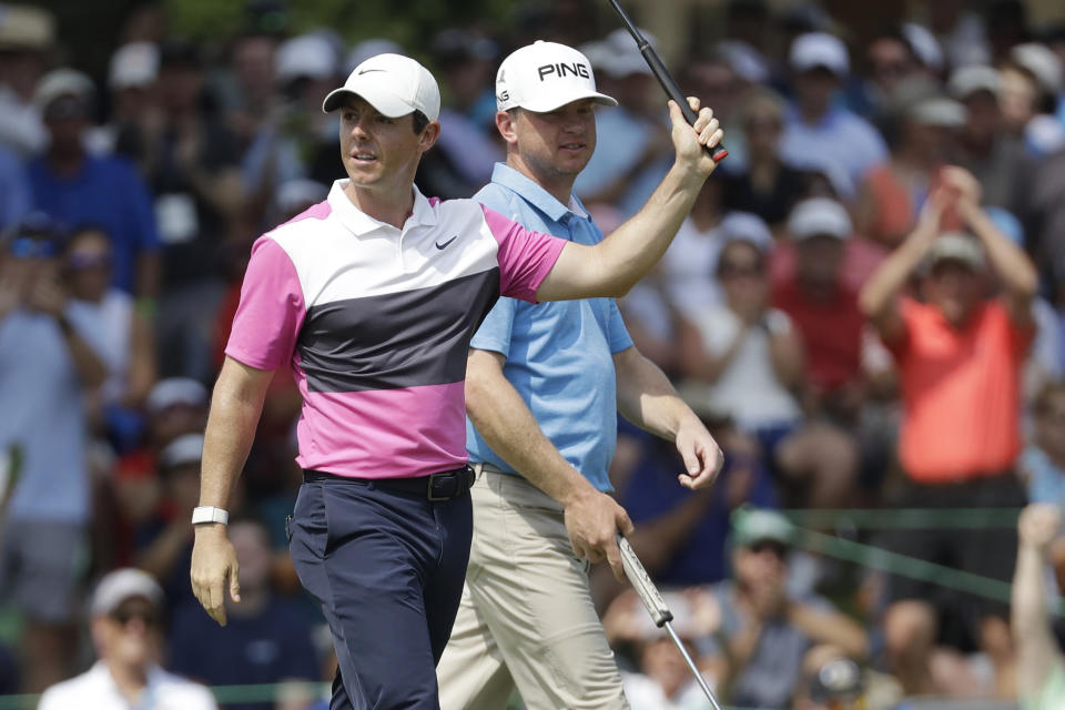 Rory McIlroy, left, of Northern Ireland, waves to the crowd after sinking his birdie putt on the 18th green to give him the lead during the third round of the World Golf Championships-FedEx St. Jude Invitational Saturday, July 27, 2019, in Memphis, Tenn. McIlroy's playing partner Nate Lashley, right, looks on. (AP Photo/Mark Humphrey)
