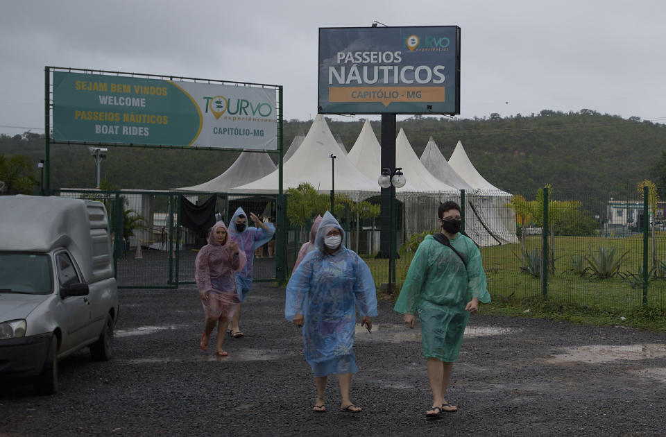 Tourists leave a pier at the Furnas reservoir, a day after a massive slab of rock broke away from a cliff and toppled onto pleasure boaters on Saturday, killing at least seven people, near Capitolio city, Brazil, Sunday, Jan. 9, 2022. (AP Photo/Igor do Vale)