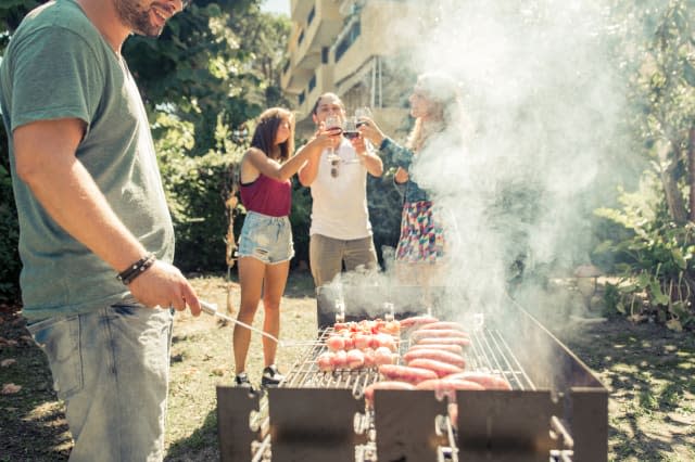 Group of friends making barbeque in the backyard