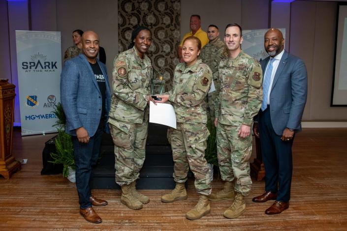 Staff Sgt. Audreianor Handsome-Crawford from the 42nd Logistics Readiness Squadron, poses for a photo with MGMWERX director Trent Edwards, Col. Eries Mentzer, Chief Master Sgt. Lee Hoover, and Terence Henderson during Spark at the Max, April 14, 2022.