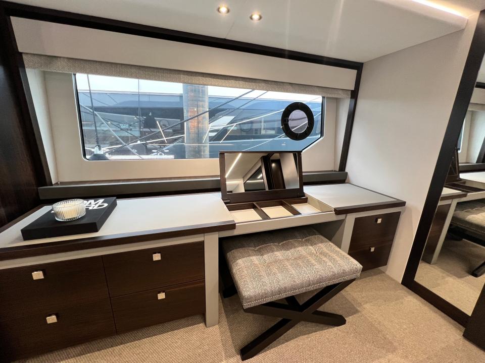 The long dressing table with six wooden drawers and grey top in front of long window in master cabin of Sunseeker 76