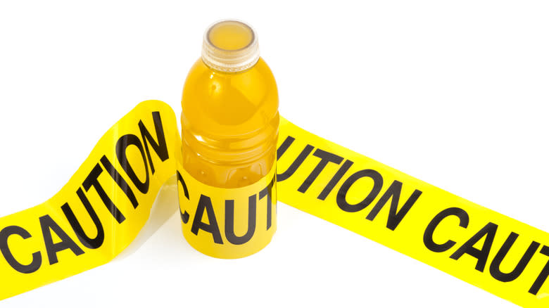 Yellow sports drink wrapped in caution tape