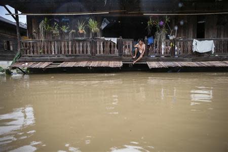 A man sits on the second floor of his house, affected by floodwaters, at Kabin Buri district in Prachin Buri September 29, 2013. REUTERS/Athit Perawongmetha