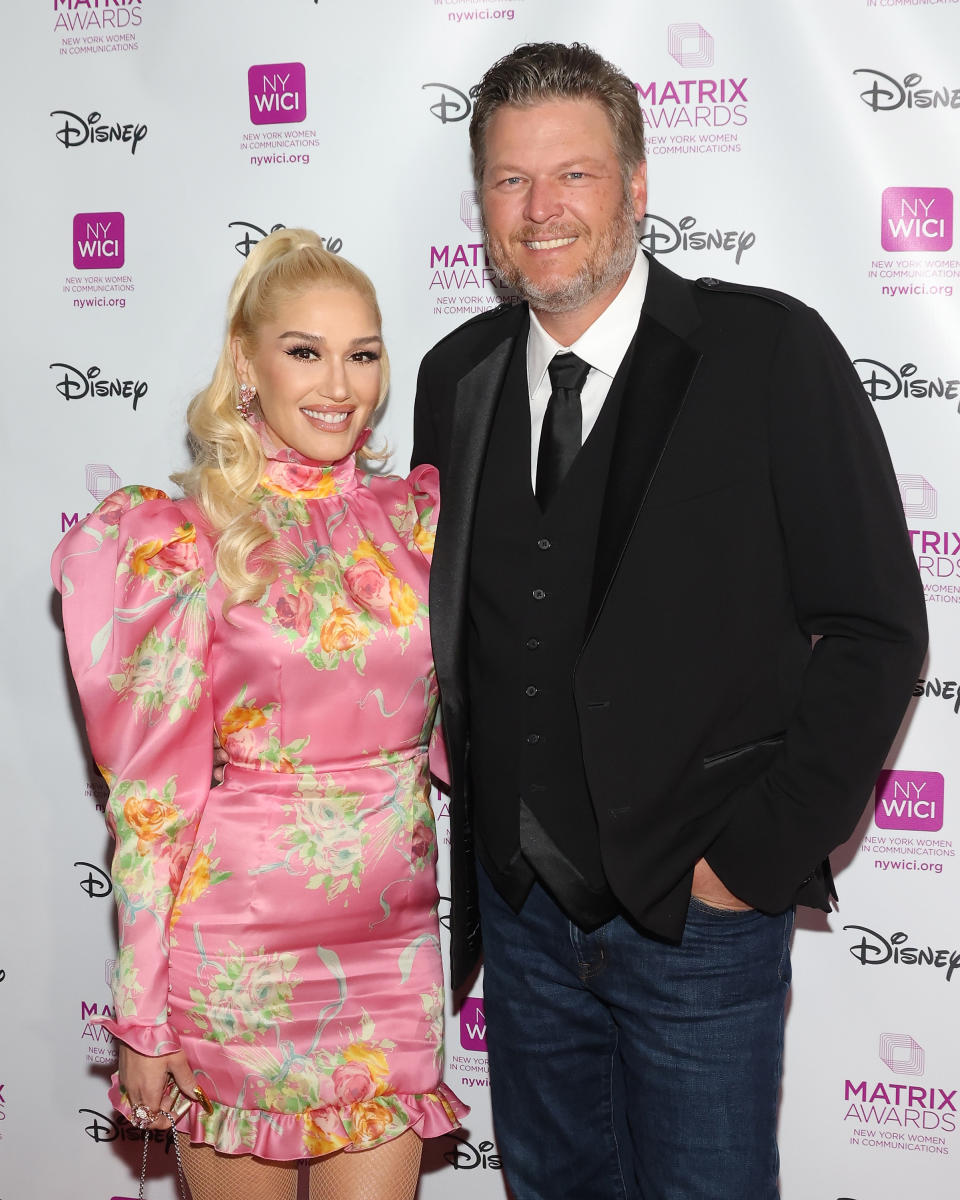 Blake Shelton next to Gwen Stefani on red carpet in floral pink dress