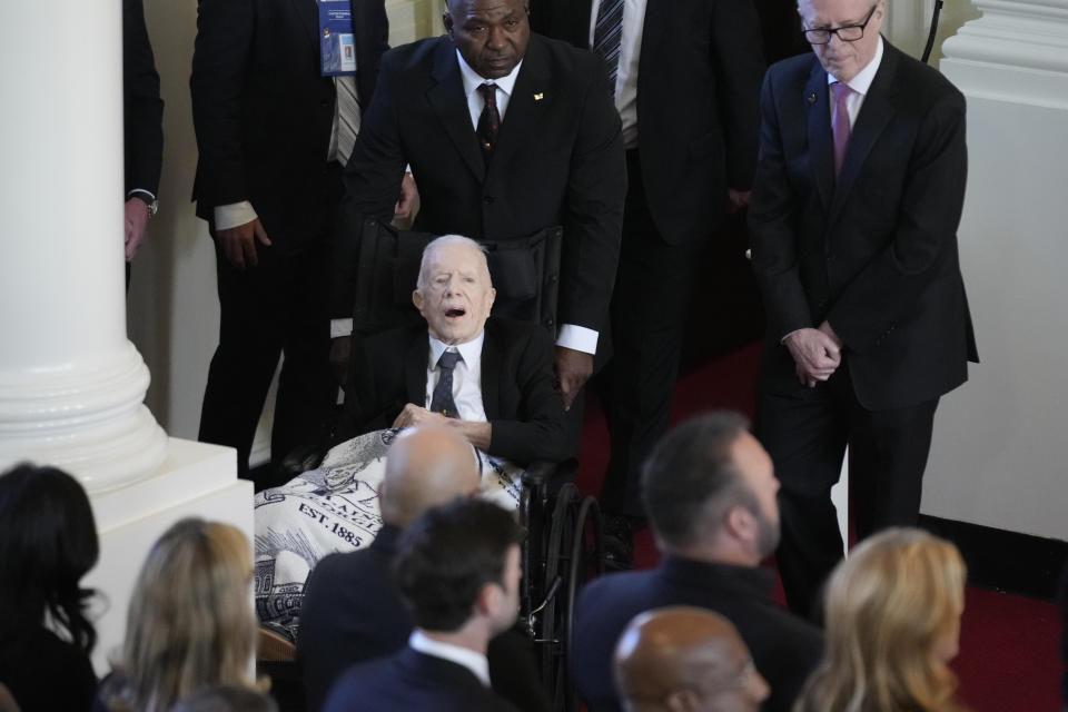 高齡99歲前美國總統卡特（坐輪椅者）28日公開現身出席愛妻羅莎琳（Rosalynn Carter）的追悼會。（美聯社）