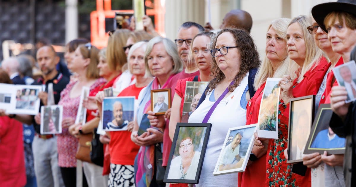 People hold pictures of loved ones lost during the pandemic outside the UK Covid-19 Inquiry at Dorland House in London (PA)