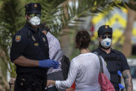 Police officers wearing face masks stand by as guests leave the H10 Costa Adeje Palace hotel in La Caleta, in the Canary Island of Tenerife, Spain, Saturday, Feb. 29, 2020. Some guests have started to leave the locked down hotel after undergoing screening for the COVID-19 virus. (AP Photo/Joan Mateu)