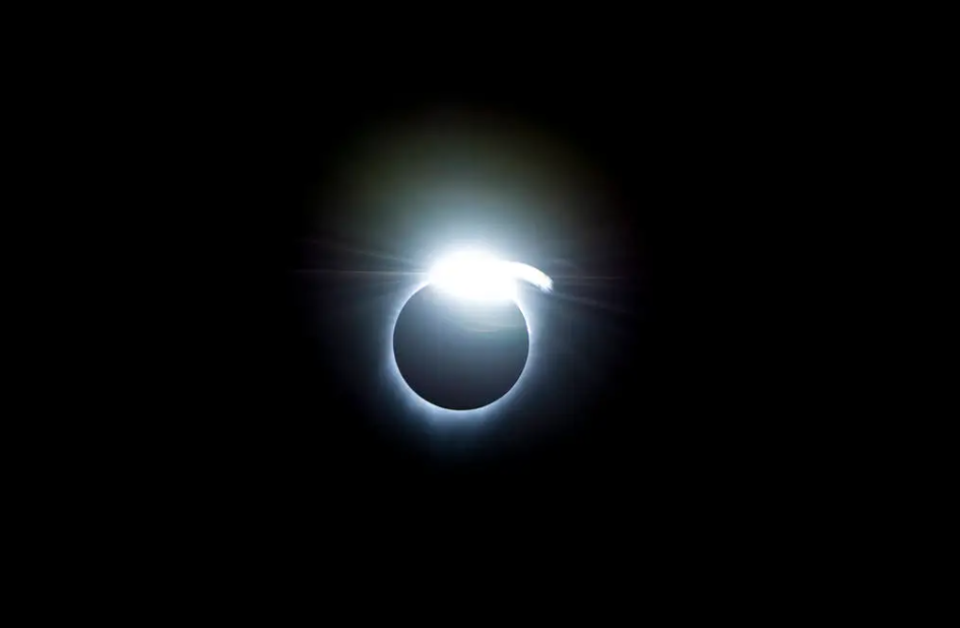 view of a solar eclipse, showing a bright ring of white light around the edge of the blocked-out sun.