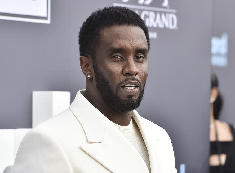 Sean Combs poses at an event in a cream suit