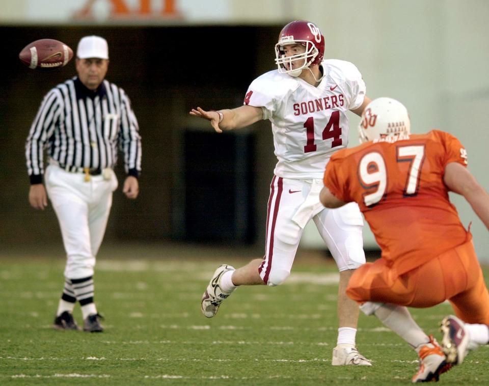 OU quarterback Josh Heupel pitches the ball in front of OSU's Zac Warner during the football game at Lewis Field in Stillwater on Nov. 25, 2000.