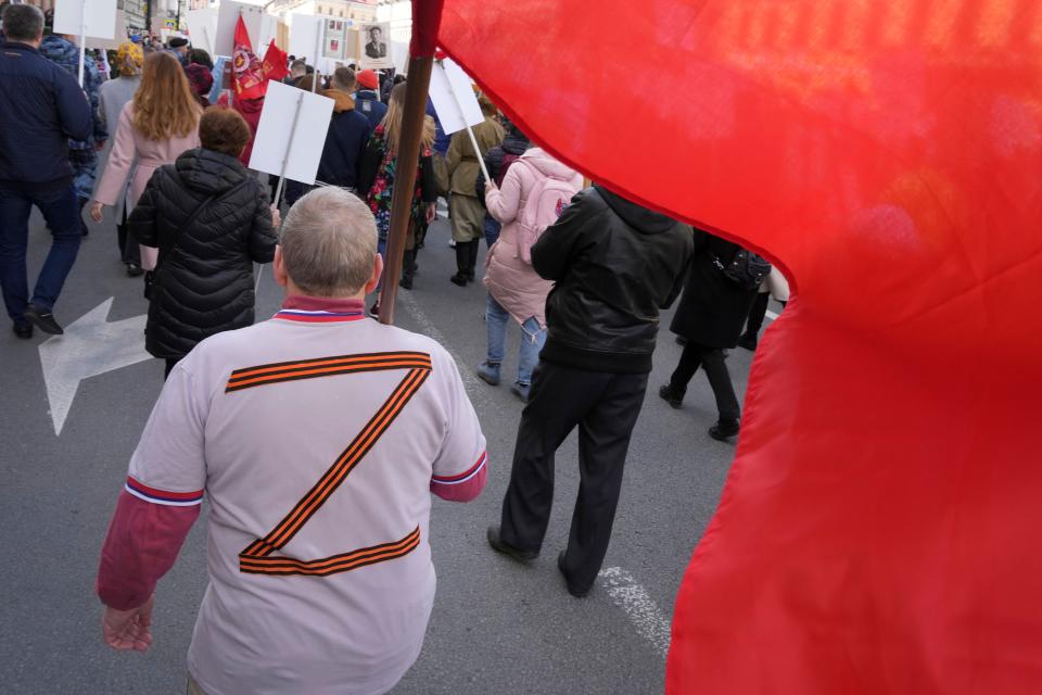 A man wearing a T-shirt with letter Z, which has become a symbol of the Russian military, carries a red banner, during the Immortal Regiment march at the Nevsky prospect, the central avenue of St. Petersburg, Russia, on May 9, 2022.