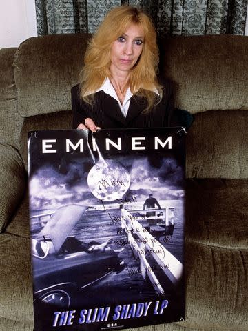 <p>Mark Weiss/Getty</p> Debbie Mathers holds a poster with a handwritten message during a portrait session at her home in September 2005 in Detroit, Michigan