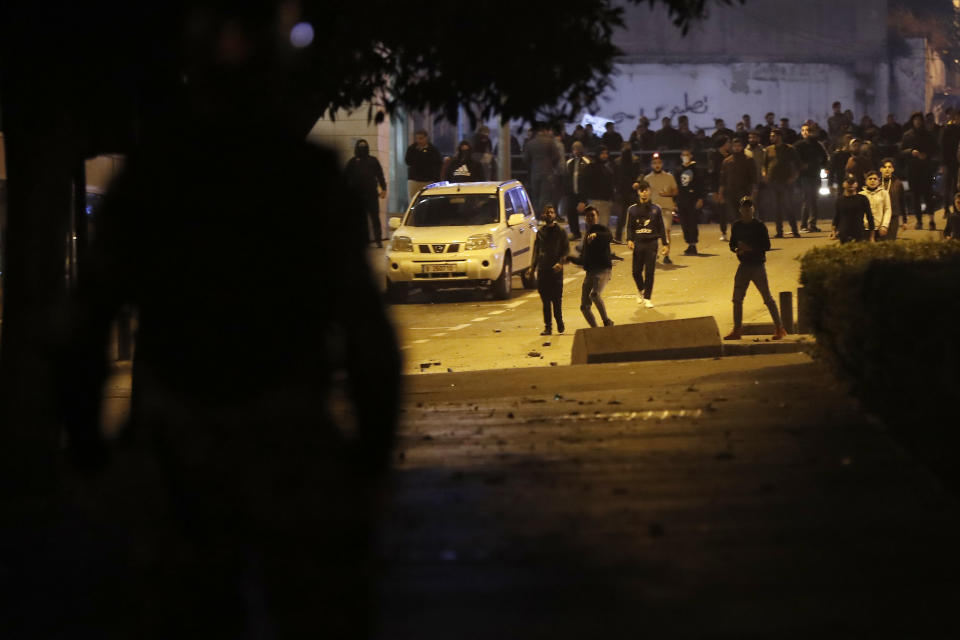 Supporters of the Shiite Hezbollah and Amal Movement groups, who are trying to attack the anti-government protesters, throw stones against the riot policemen, in Beirut, Lebanon, Wednesday, Dec. 11, 2019. Protesters are demanding a government made up of technocrats that would immediately get to work on the necessary reforms to address the economy. (AP Photo/Hussein Malla)