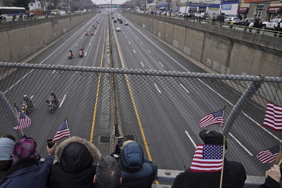 A procession carries the body of NYPD Officer Jason Rivera to a cemetery as people watch from an overpass in Yonkers, N.Y., Friday, Jan. 28, 2022. Rivera and his partner, Officer Wilbert Mora, were fatally wounded when a gunman ambushed them in an apartment as they responded to a family dispute last week. (AP Photo/Seth Wenig)