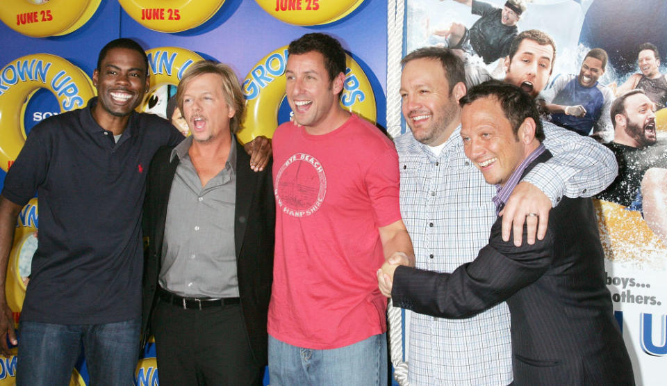 Chris Rock, David Spade, Adam Sandler, Kevin James, and Rob Schneider pose playfully in front of 