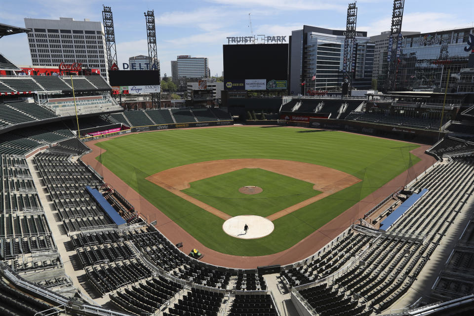 FILE - In this April 1, 2020, file photo, Atlanta Braves field manager Tyler Lenz walks across the covered home plate at Truist Park in Atlanta. There are no sponsored power plays at the moment. No doughnut races in the fourth quarter. No calls to the bullpen presented by phone companies. While the coronavirus pandemic circles the world, sports business executives are having conversations about lucrative advertising and marketing contracts with no games on the horizon. (Curtis Compton/Atlanta Journal-Constitution via AP, File)