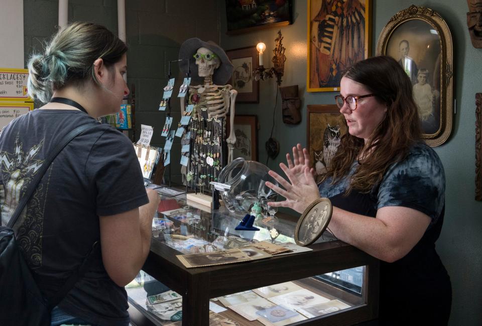 Erica Meny of Evansville listens as owner Jasmine Elzy explains uranium glass and spinel rings at Corkscrew Curiosities in Henderson, Ky., Thursday, May 12, 2022.