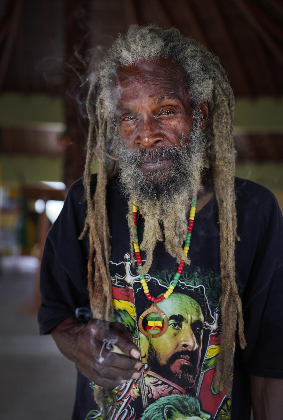 Rastafari member Jahwanzer John stands for a portrait while smoking a joint in the tabernacle after Sunday service on May 14, 2023, in Liberta, Antigua. (AP Photo/Jessie Wardarski)
