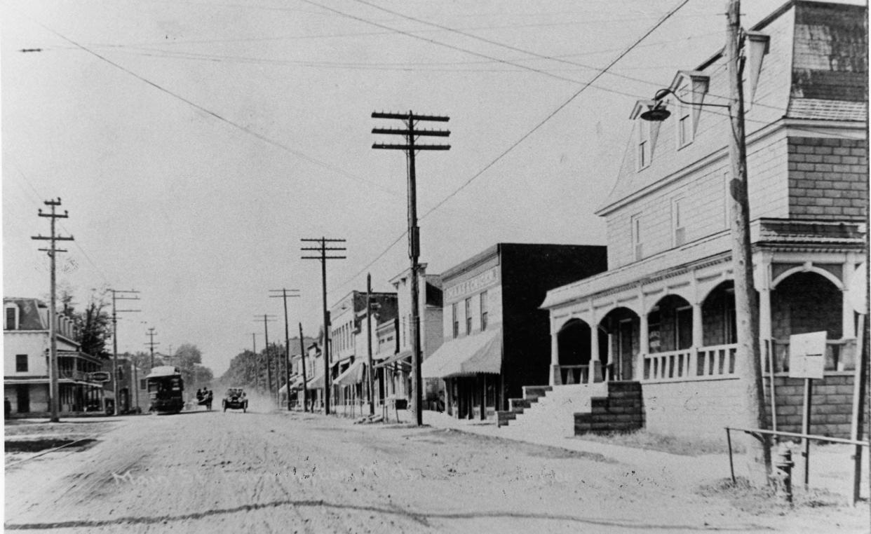 In 1800s Farmington, three modes of transportation on Grand River face west: a streetcar, automobile, and horse and buggy.