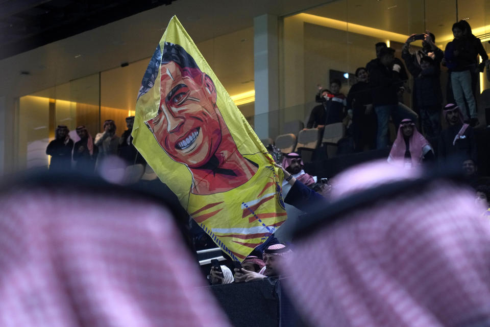 A Saudi soccer fan waves a flag with image of Al Nassr's Cristiano Ronaldo during the Riyadh Season Cup soccer match between Inter Miami and Al Nassr at Kingdom Arena Stadium in Riyadh, Saudi Arabia, Thursday, Feb. 1, 2024. (AP Photo/Amr Nabil)