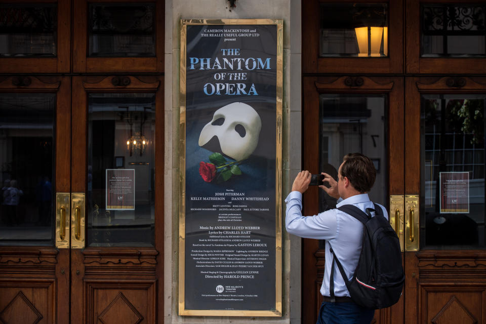 A man takes pictures of the signs at Her Majesty's Theatre, home of the Phantom of the Opera