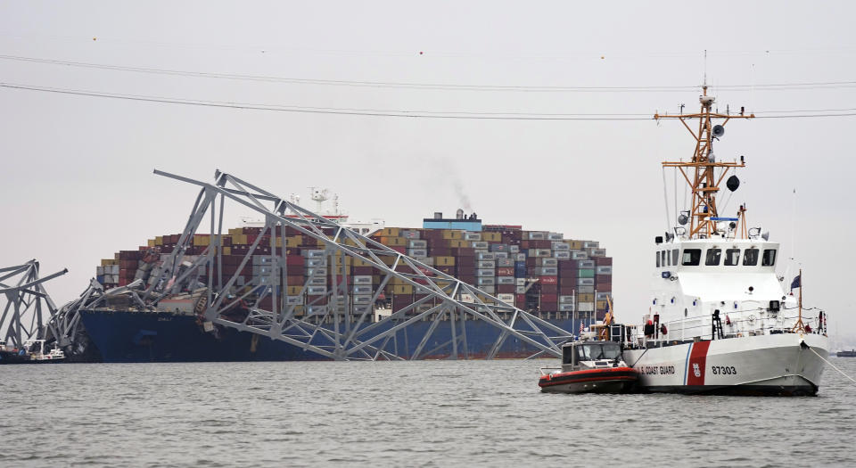 A Coast Guard cutter patrols in front of a cargo ship that is stuck under the part of the structure of the Francis Scott Key Bridge after the ship hit the bridge Wednesday, March 27, 2024, in Baltimore, Md. (AP Photo/Steve Helber)