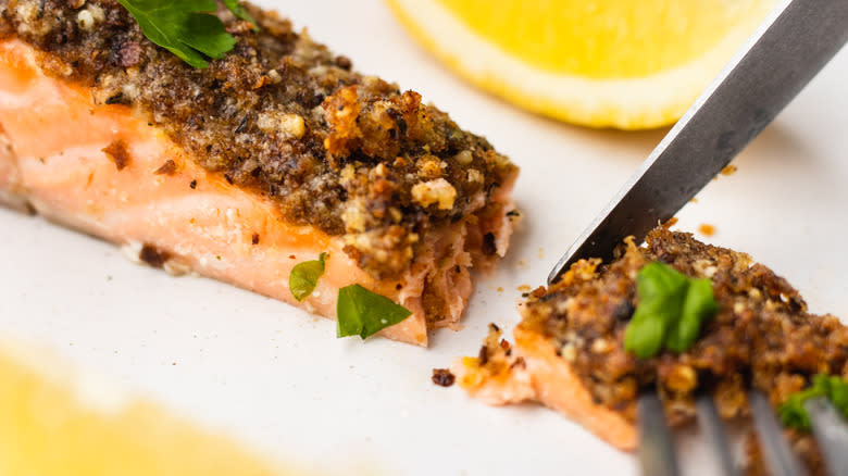 cutting into Parmesan-crusted salmon