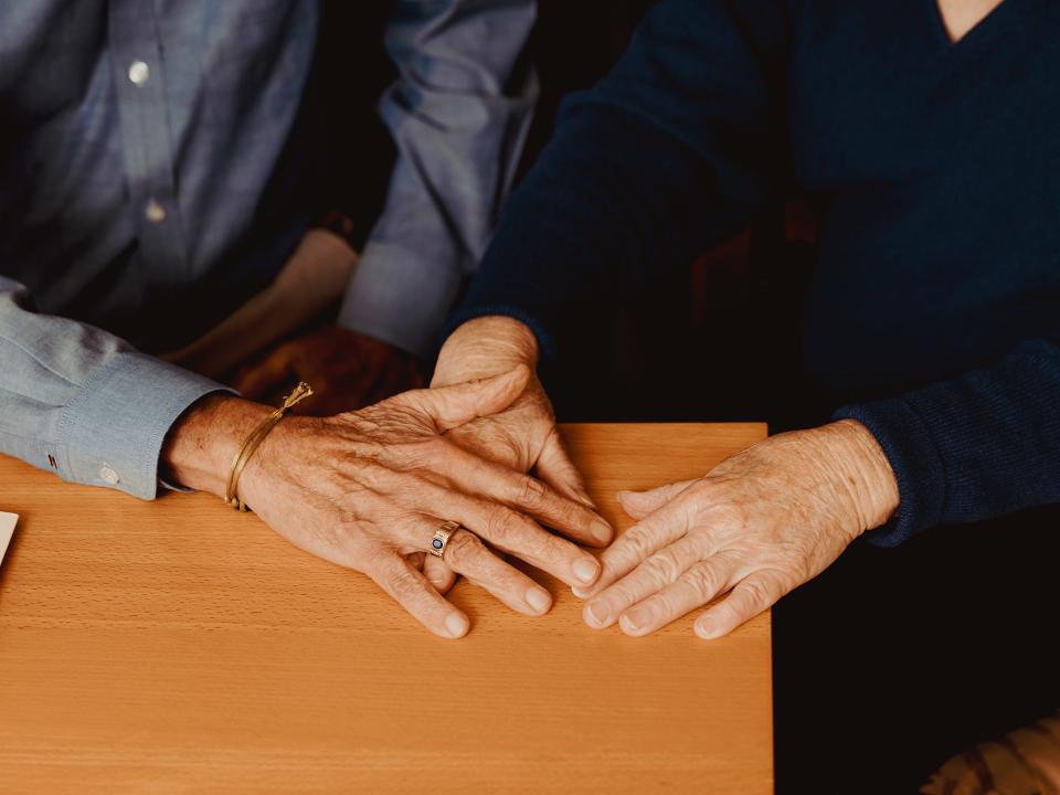 Older couple holding hands on table