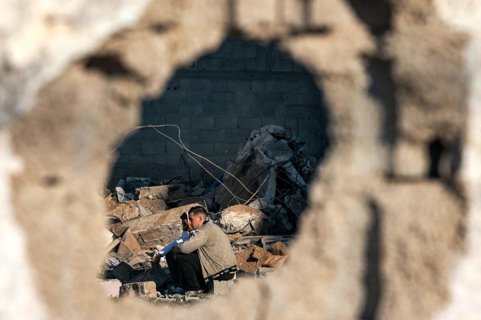 People gather to inspect the rubble of a building destroyed by Israeli bombardment in Rafah in the southern Gaza Strip on December 19, 2023 amid continuing battles between Israel and the militant group Hamas.