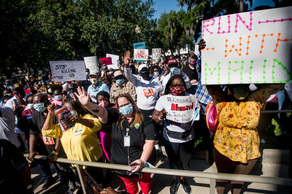 Demonstrators gather with signs and masks to protest the shooting death of Ahmaud Arbery.