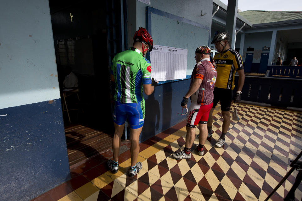 Ciclistas buscan por sus nombres en un centro de votación en la segunda ronda presidencial en San José, Costa Rica, el domingo 6 de abril de 2014. (AP Photo/Moises Castillo)