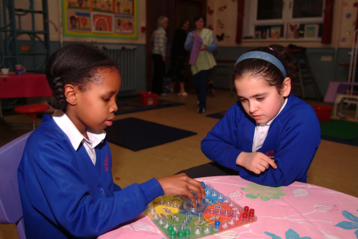 Youngsters at an after-school club playing a board game (Alamy/PA)