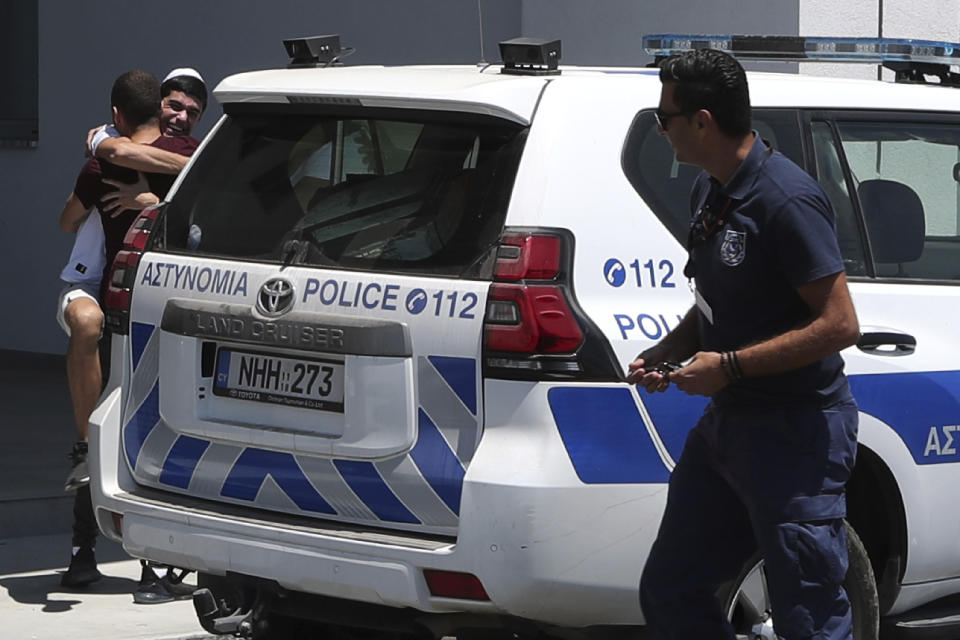 An Israeli teenager is embraced by relatives after being released from Famagusta police headquarters in southeast town of Paralimni, Cyprus, Sunday, July 28, 2019. A lawyer says Cyprus police will release all seven Israeli teenagers who were being detained as suspects in the alleged rape of a 19-year-old British woman. Cypriot Lawyer Yiannis Habaris, who represents two of the seven Israelis, told The Associated Press on Sunday the British woman has been arrested and faces a public nuisance charge. (AP Photo/Petros Karadjias)