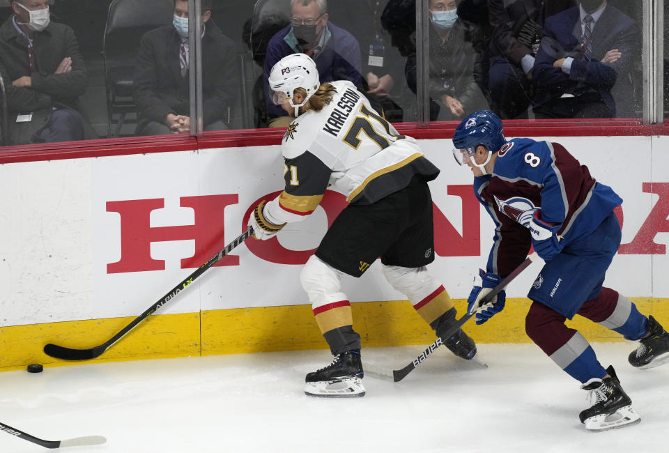 Vegas Golden Knights center William Karlsson, left, reaches out to control the puck as Colorado Avalanche defenseman Cale Makar covers in the first period of an NHL hockey game Tuesday, Oct. 26, 2021, in Denver. (AP Photo/David Zalubowski)