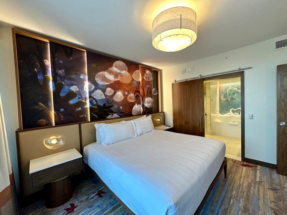 Fantasia-themed two-bedroom villa at Disneyland with movie-inspired mural on headboard and plain white bed