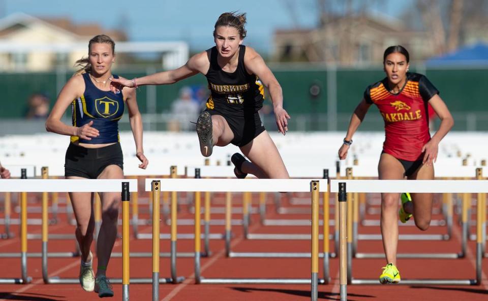 Hughson’s Logann Meyer hurdles to victory with a time of 16.13 in the 100 meter hurdles during the Stanislaus County track meet at Hughson High School in Hughson, Calif., Friday, March 24, 2023. Turlock’s Ella Spaulding finished second and Oakdale’s Kylie Nunes, right, finished third.