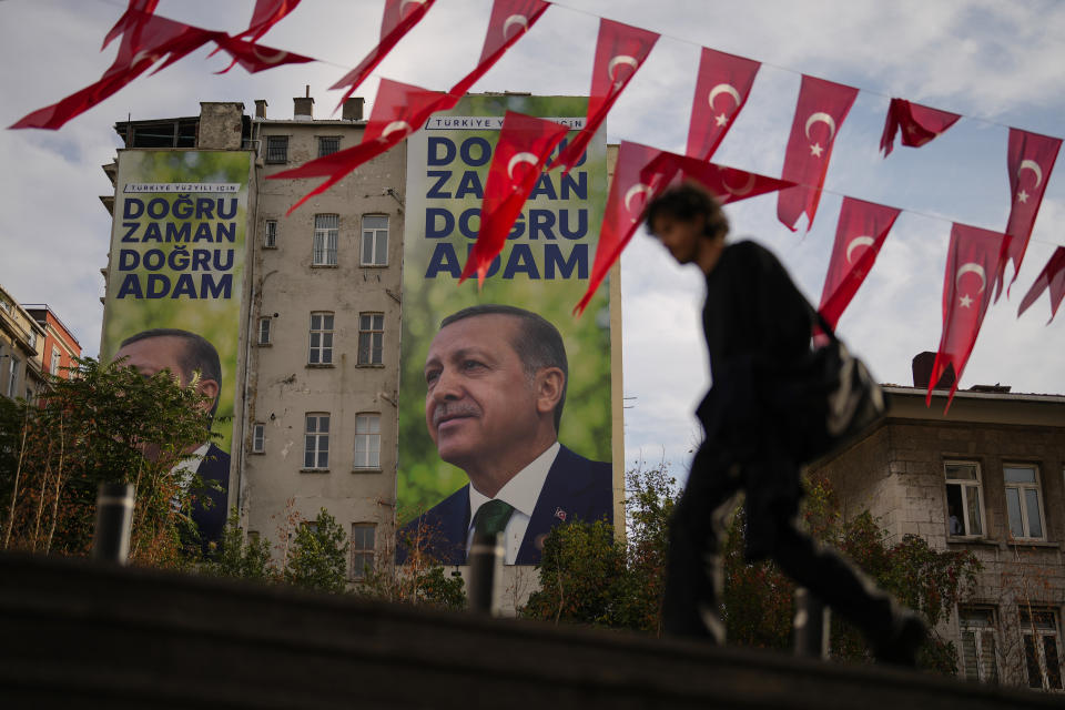 A man walks past billboards displaying Turkish President Recep Tayyip Erdogan and read in Turkish: "For the Turkish century, the right time, the right man" in Istanbul, Turkey, Friday, Nov. 3, 2023. Turkey is marking its centennial but a brain drain is casting a shadow on the occasion. Government statistics indicate that a growing number of the young and educated are looking to move abroad in hopes of a better life, mainly in Europe. (AP Photo/Francisco Seco)