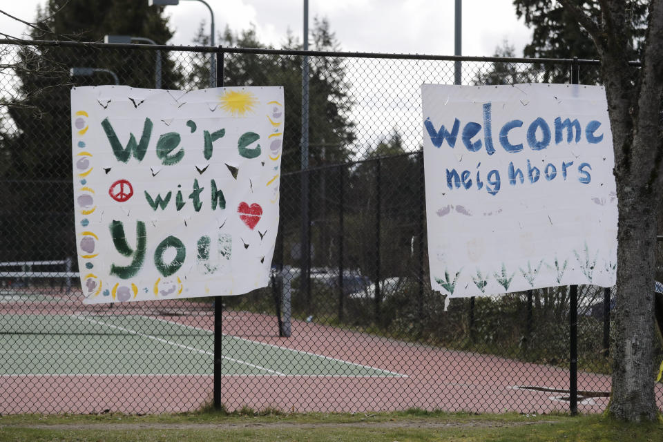 In this photo taken Tuesday, March 24, 2020, handmade signs posted to a tennis court fence are set to greet future patients at a temporary field hospital for coronavirus patients on an adjacent soccer field in the Seattle suburb of Shoreline, Wash. With U.S. hospital capacity stretched thin, hospitals around the country are scrambling to find space for a coming flood of COVID-19 patients, opening older closed hospitals and repurposing other buildings. (AP Photo/Elaine Thompson)