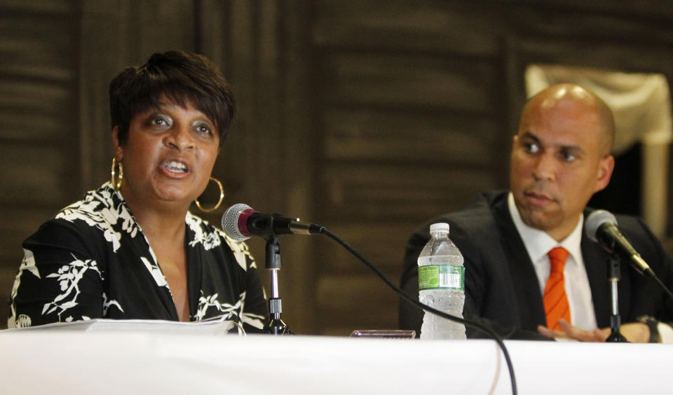 In this July 26, 2010 photo, Linda Watkins-Brashear, left, executive director of the Newark Watershed Conservation and Development Corporation, presents the case for the Newark Municipal Utilities Authority (MUA) as Newark Mayor Cory Booker, right, listens during a Newark Municipal Council public hearing regarding the creation of the Newark Municipal Utilities Authority in Newark, N.J. As a Democratic presidential candidate, Booker has leaned heavily on his record as Newark mayor. But the watershed scandal still burns some of his critics in New Jersey. A state investigation blasted Booker and his administration for failing to exercise oversight over the group’s operations. (Tim Farrell/NJ Advance Media via AP)