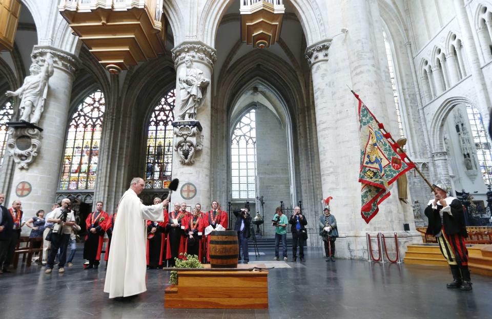 A priest blesses a barrel of beer as members of the Knighthood of the Brewers' Mash staff take part in celebrations of Saint-Arnould, during a mass at the Sint-Gudule Cathedral in Brussels