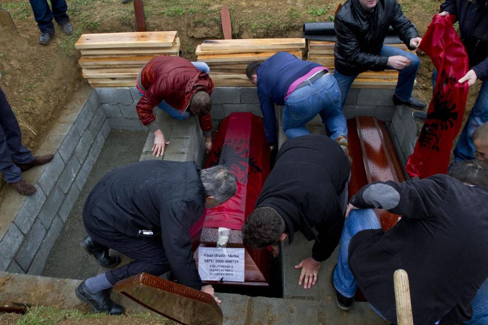 Ethnic Albanians bury a coffin draped with an Albanian flag, centre, containing the remains of ethnic Albanian Visar Shehu killed during 1998-99 Kosovo war in the town of Mala Krusa during the funeral ceremony on Wednesday, March 26, 2014. The victims were killed in two separate rampages by Serbs forces in town of Suva Reka and Mala Krusa just days after NATO began a bombing campaign to end an onslaught by Serbia on separatist ethnic Albanians. (AP Photo/Visar Kryeziu)