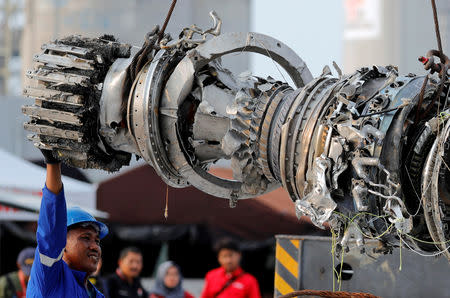 A worker assists his colleague during the lifting of a turbine engine of the Lion Air flight JT610 jet, at Tanjung Priok port in Jakarta, Indonesia, November 4, 2018. Picture taken November 4, 2018. REUTERS/Beawiharta