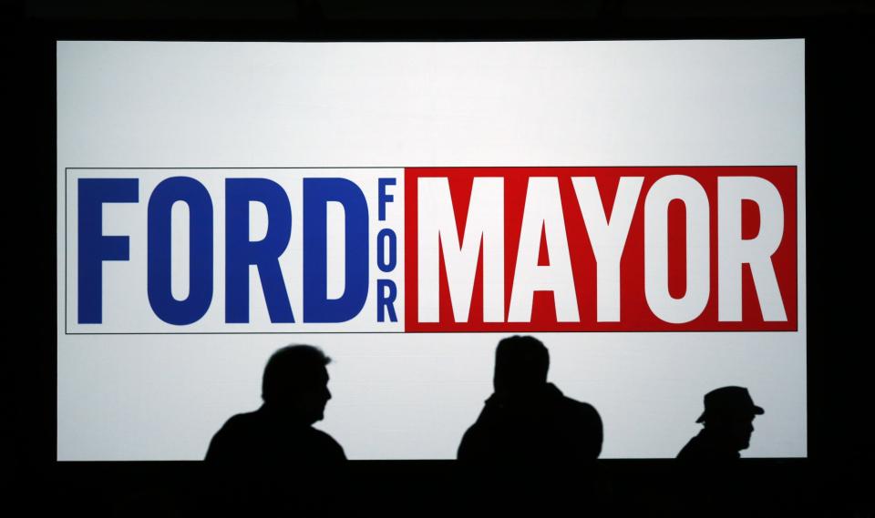 People are silhouetted in front of a sign at Toronto Mayor Rob Ford's campaign launch party in Toronto, April 17, 2014. The Toronto municipal election is set for October 2014.