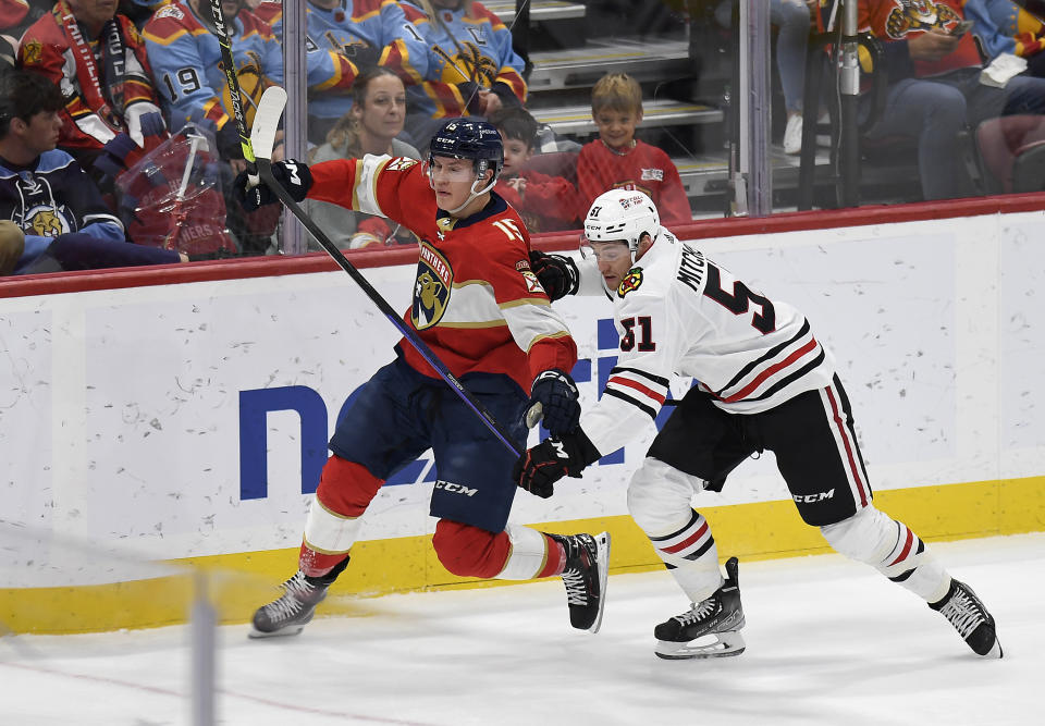 Florida Panthers center Anton Lundell (15) races Chicago Blackhawks defenseman Ian Mitchell (51) to the puck during the first period of an NHL hockey game, Friday, March 10, 2023, in Sunrise, Fla. (AP Photo/Michael Laughlin)