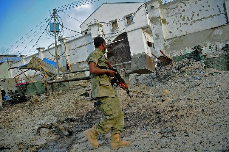 A solder walks past at the scene of a car bomb attack and armed raid by Shebab militants on the Maka al Mukarama hotel in Mogadishu on March 27, 2015