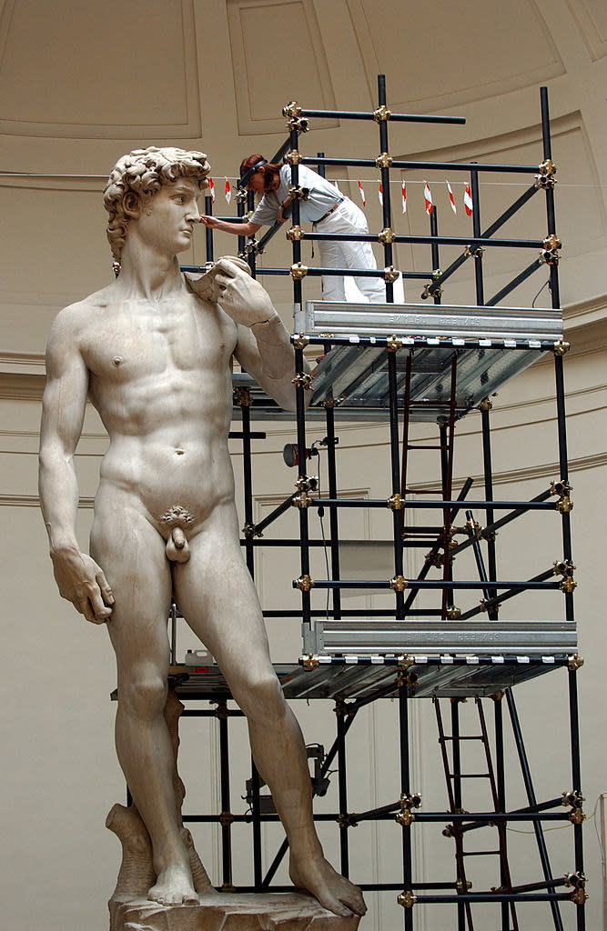 A man on a ladder maintaining the "David" statue