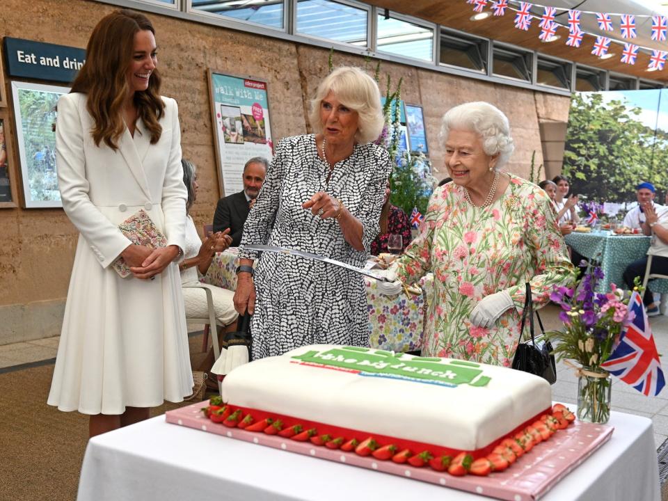 Queen Elizabeth cuts cake with sword while Kate Middleton looks on