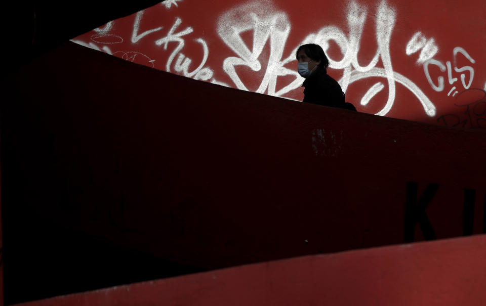 A woman wearing a face mask walks in Prague, Czech Republic, Tuesday, Oct. 20, 2020. Facing a record surge of coronavirus infections, the Czech Republic returns to a recipe that was believed to work well to contain the pandemic in the spring. Starting Wednesday, face masks will be again mandatory outdoors. (AP Photo/Petr David Josek)